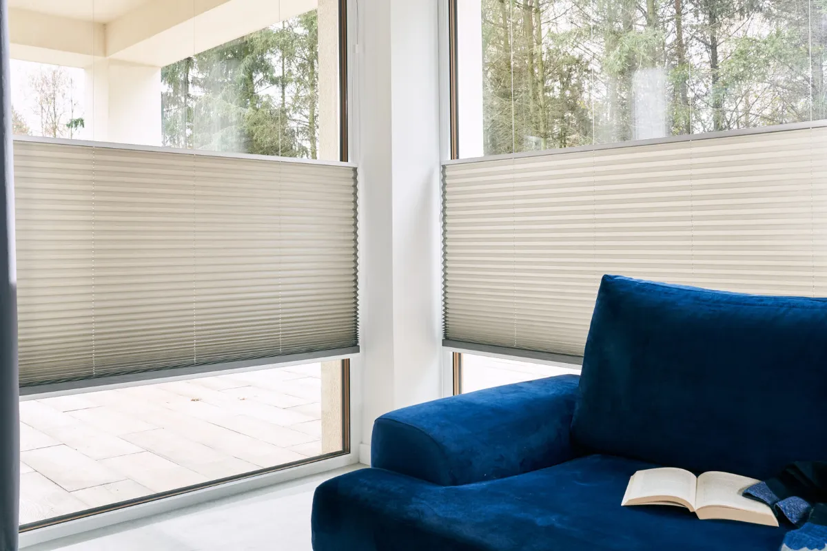 Weiße Plissees an Fenster mit blauem Sessel